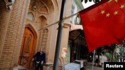 An elderly man is seen behind a Chinese national flag in the Old City in Kashgar in Xinjiang Uighur Autonomous Region, China September 6, 2018. (REUTERS/Thomas Peter)