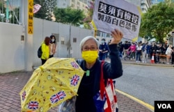 64岁的示威者黄婆婆手持标语及黄伞12月2日到西九龙裁判法院外声援被判入狱的黄之锋、林朗彦及周庭。