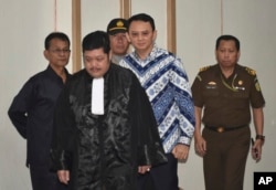 FILE - Jakarta Governor Basuki "Ahok" Tjahaja Purnama, center, is escorted by prosecutors as enters the court room for his sentencing hearing in Jakarta, Indonesia, May 9, 2017.