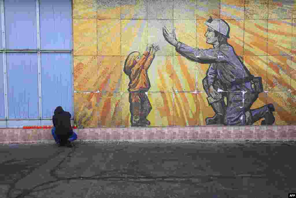 A man lights candles at a temporary memorial at the coal mine at Stonava, near Karvina, Czech Republic, a day after 13 miners died in an accident.