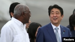 Japan's Prime Minister Shinzo Abe, center, talks to Salvador Antonio Valdes Mesa, a member of the Political Bureau of the Central Committee of the Communist Party of Cuba and vice president of the Council of State of Cuba, upon his arrival at Jose Marti International Airport in Havana, Cuba, Sept. 22, 2016. 