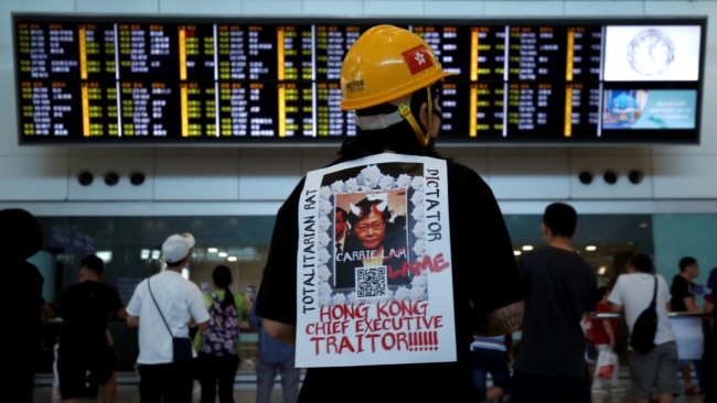 一名示威者在香港机场背负一张称香港特首林郑月娥为独裁者的抗议标语。（2019年7月26日）