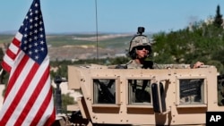 In this April 4, 2018 file photo, a U.S. soldier sits on his armored vehicle on a road leading to the tense front line in Manbij, Syria.