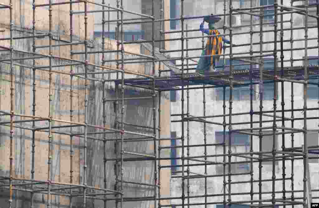 An Indian labourer works on a construction site during heavy smog conditions in New Delhi.