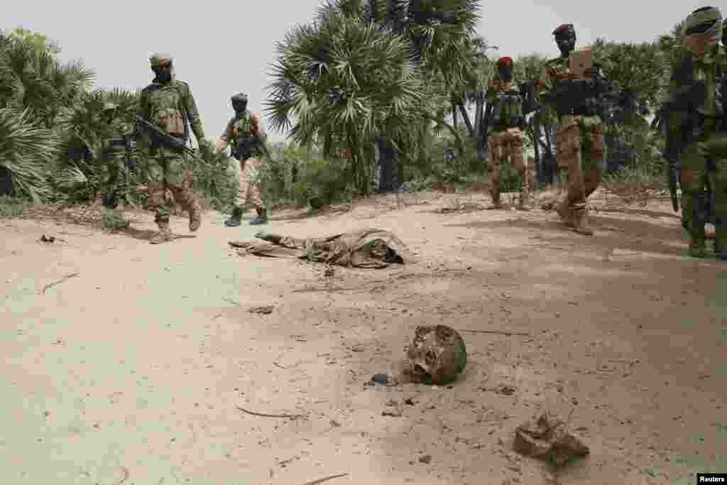 Des soldats tchadiens et nigériens en patrouille, regardent des cadavres en décomposition dans une fosse commune dans la ville de Damasak récemment reprise de mains de Boko Haram, le Nigeria, vendredi 20 mars 2015.