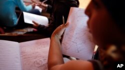 FILE -- Children learn how to describe parts of the human body during English class at a makeshift camp of migrants and refugees at the northern Greek border point of Idomeni, Greece, Monday, May 2, 2016. Starting Monday, Greece will begin schooling about 1,500 migrant children.