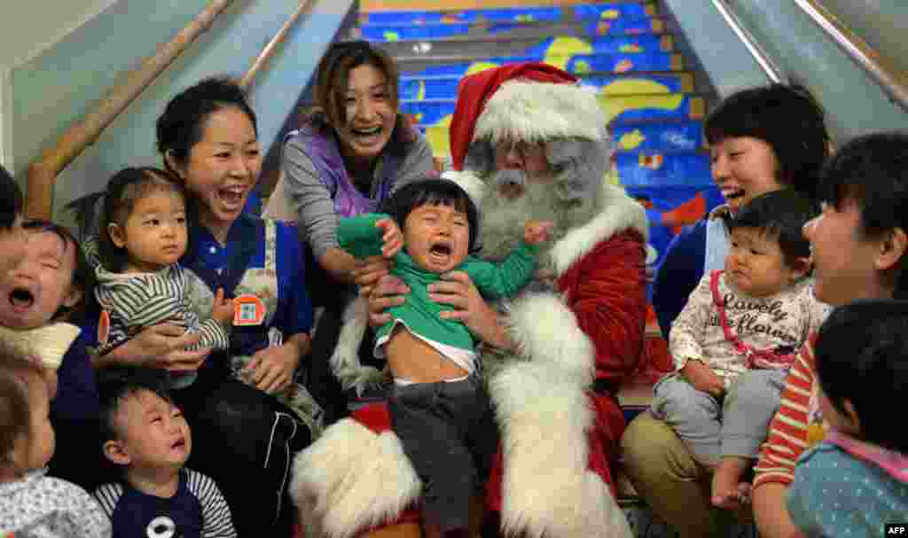 A man playing Santa Claus from Finland sits with children at the Hinomoto nursery school in Tokyo, Japan.