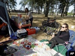 Hilary O'Hollaren, right, sits in the early morning sun as Rory O'Hollaren prepares breakfast as they camp near the state fairgrounds in preparation for the Aug. 21, 2017, solar eclipse in Salem, Ore.
