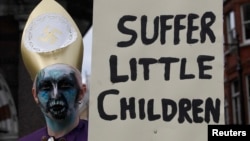 پادریوں کی بچوں سے جنسی زیادتیوں کے خلاف مظاہرے میں ایک شخص بینر اٹھائے ہوئے ہے۔ فائل فوٹو