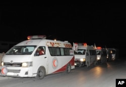FILE - In this photo released by the Syrian official news agency SANA, ambulances of the Syrian Arab Red Crescent line up during a mission to evacuate sick and wounded people from Eastern Ghouta, near Damascus, Syria, Dec. 28, 2017.