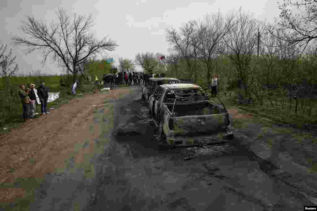 Local residents look at burned out cars near a checkpoint that was the scene of a gunfight overnight near the city of Slaviansk, Ukraine, April 20, 2014.&nbsp;