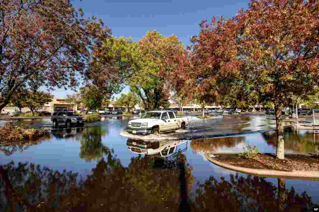 A pickup truck crosses a flooded parking lot in Oroville, Calif., Oct. 25, 2021. A massive storm barreled toward Southern California after causing flooding across the northern half of the state.