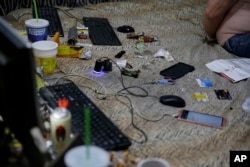 Smartphones, credit cards, food wrappers and cigarettes are found on the bed of suspected child webcam cybersex operator, David Timothy Deakin, from Peoria, Ill., during a raid in Mabalacat, Philippines, April 20, 2017.