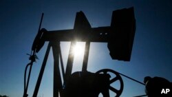 An oil well pumps under the summer sun in a field near Rantoul, Kan., Friday, July 1, 2011.