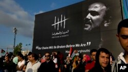 FILE - Protesters hold a banner with a picture of jailed Palestinian uprising leader Marwan Barghouti during a rally supporting Palestinian prisoners in Israeli jails on a hunger strike, in the West Bank city of Ramallah, May 3, 2017.