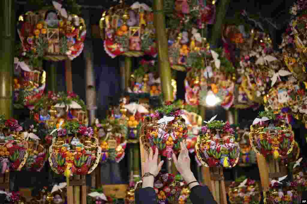 A worker displays various "Kumade" or "good luck rake" to sell during the Torinoichi festival at a shrine in Tokyo, Japan.