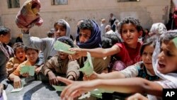 FILE - Yemenis present documents in order to receive food rations provided by a local charity, in Sana'a, Yemen, April, 13, 2017. 