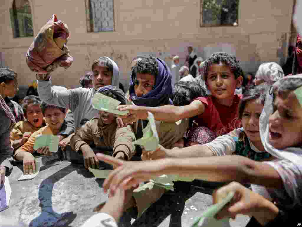 Remaja dan anak-anak Yaman menunjukkan surat untuk menerima bantuan makanan dari sebuah yayasan sosial setempat di Sana&#39;a.
