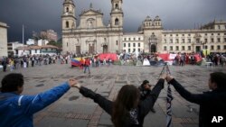  FILE - Demonstrators hold hands to support a peace accord between the Colombian government and rebels of the Revolutionary Armed Forces of Colombia, FARC, at the main square in Bogota, Colombia, Oct. 8, 2016.