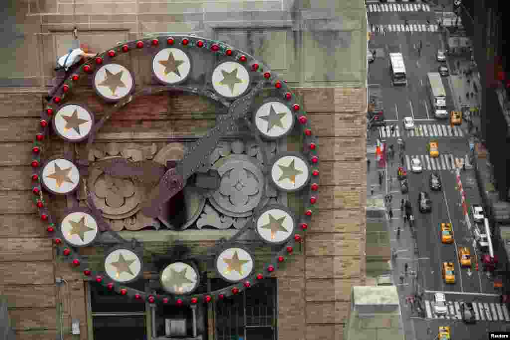 A worker replaces lightbulbs of a clock above Times Square on the Paramount building in New York City.