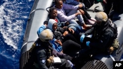 FILE - Rescued migrants sit in a German Navy boat besides Finish Special Forces, prior to board the German combat supply ship 'Frankfurt am Main' during EUNAVFOR MED Operation Sophia in the Mediterranean Sea off the coast of Libya, March 29, 2016. The MSF has relaunched rescue operations in the Mediterranean Sea, accusing European governments of failing to act to save migrants in peril at sea.