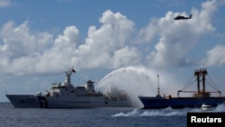 FILE - A Taiwan Coast Guard ship, left, extinguishes a fire on a cargo ship during a rescue drill near the coast of Itu Aba, which the Taiwanese call Taiping, at the South China Sea, Nov. 29, 2016.