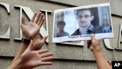 FILE - A supporter holds a picture of Edward Snowden, a former CIA employee who leaked top-secret information about U.S. surveillance programs, outside the U.S. Consulate General in Hong Kong, June 13, 2013. 