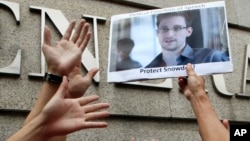 A supporter holds a picture of Edward Snowden, a former CIA employee who leaked top secret information about U.S. surveillance programs, outside the U.S. Consulate General in Hong Kong Thursday, June 13, 2013. 