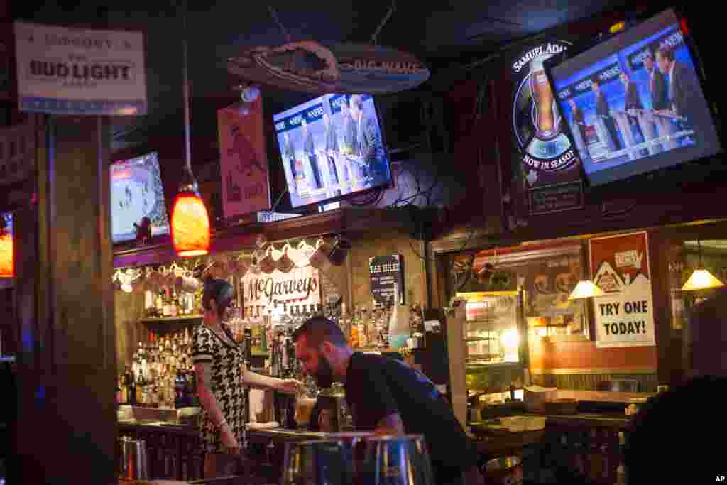 Bartenders work at McGarveys Bar in Manchester, N.H., as the Republican presidential debate is shown on televisions