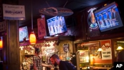 Bartenders work at McGarveys Bar in Manchester, N.H., as the Republican presidential debate is shown on televisions