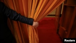 FILE - A security agent opens a curtain covering the entrance of a main hall inside the Great Hall of the People where sessions of the National People's Congress and the Chinese People's Political Consultative Conference take place, in Beijing, China, March 6, 2016. 