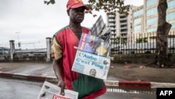 A newspaper vendor looks for customers at a street light in Libreville on Aug. 29, 2016 while displaying local papers reporting on the outcome of Gabons's presidential elections.