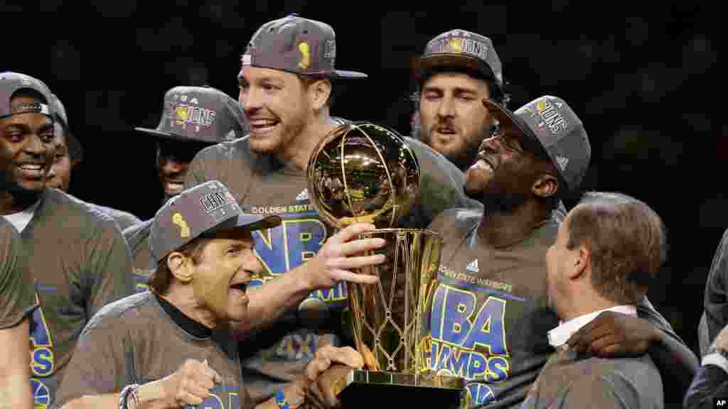 Trophée en main, les Golden State Warriors célèbrent avec les propriétaires du club Peter Guber, à gauche, et Joe Lacob, &nbsp;après avoir remporté la finale NBA contre les Cavaliers de Cleveland, &nbsp;mercredi 17 Juin 2015.