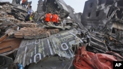 Para penyelidik memeriksa puing-puing pesawat Hercules milik Angkatan Udara yang jatuh di Medan (1/7). (AP/Binsar Bakkara)