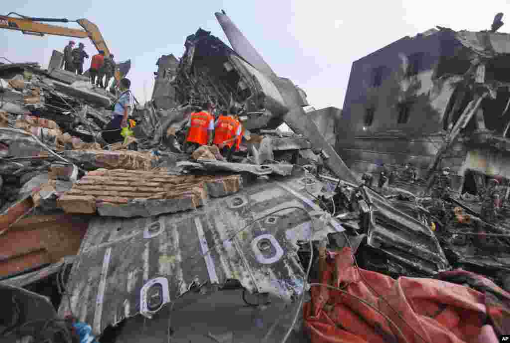 Para penyelidik memeriksa puing-puing pesawat Hercules milik Angkatan Udara yang jatuh di Medan (1/7). (AP/Binsar Bakkara)