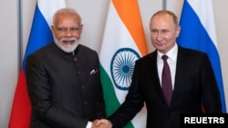 Russian President Vladimir Putin, right, shakes hands with Indian Prime Minister Narendra Modi during their meeting on the sideline of the 11th edition of the BRICS Summit, in Brasilia, Brazil November 13, 2019. Pavel Golovkin/Pool via REUTERS
