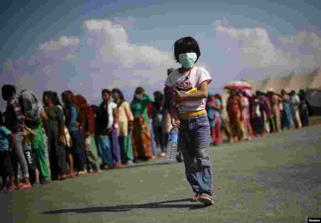 A displaced earthquake victim carries food and water after collecting them from a distribution center at an open ground, in Kathmandu, Nepal, May 4, 2015.