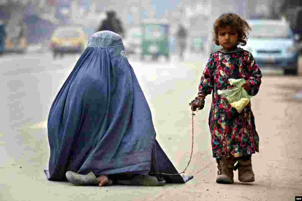 파키스탄 페샤와르의 도로에서 부르카를 쓴 여성이 딸과 함께 구걸하고 있다.