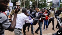 FILE - An activist opposed to the extension of presidential age limits is arrested and carried off by uniformed and plain-clothes police, while shouting for America and Israel to come to the rescue of Ugandans, near the Parliament building in Kampala, Uganda, Sept. 21, 2017.