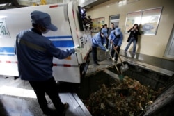 FILE - Workers unload kitchen garbage from a residential community at a closed cleaning station in downtown Beijing, China, March 30, 2017.