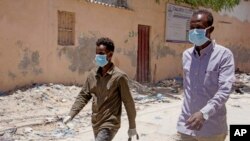 Somali men wear surgical masks on the street after after the government announced the closure of schools and universities and banned large gatherings, Mogadishu, March 18, 2020.