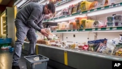 FILE - A worker removes expired food in a local supermarket in Brussels, Jan. 16, 2017.