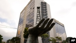 Una escultura de una mano sosteniendo un pozo petrolero junto a la petrolera estatal Petróleos de Venezuela S.A. (PDVSA), detrás, en Caracas, Venezuela.