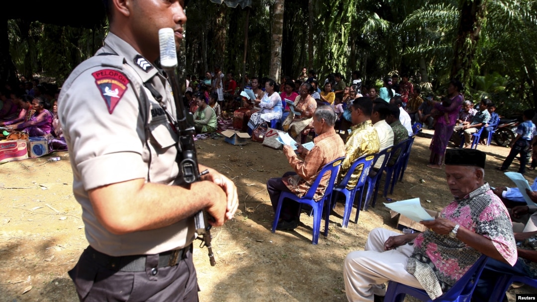 Polisi menjaga warga Kristiani di desa Suka Makmur, kabupaten Singkil, provinsi Aceh yang melakukan misa di lapangan terbuka pasca kerusuhan di Singkil tahun lalu, Minggu 18 Oktober 2015 (foto: dok).