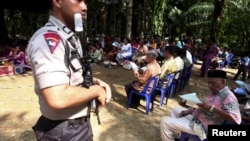 Polisi menjaga warga Kristiani di desa Suka Makmur, kabupaten Singkil, provinsi Aceh yang melakukan misa di lapangan terbuka pasca kerusuhan di Singkil tahun lalu, Minggu 18 Oktober 2015 (foto: dok).