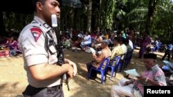 Seorang polisi memegang senjata dan berjaga-jaga sepanjang kebaktian Minggu di samping gereja yang dibakar di desa Suka Makmur di Singkil, Aceh, 18 Oktober 2015. (REUTERS/YT Haryono)