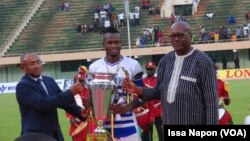 Le président de la CAF, Ahmad Ahmad (à g.), et le président du Burkina Faso, Roch Kaboré (à dr.), ont remis la Coupe du Faso au capitaine d'EFO, Ouagadougou, le 5 août 2017. (VOA/Issa Napon)