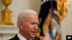 President Joe Biden speaks about the coronavirus, accompanied by Vice President Kamala Harris, in the State Dinning Room of the White House, Jan. 21, 2021, in Washington.