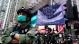 A police officer displays a warning banner on China's National Day in Causeway Bay, Hong Kong, Thursday, Oct. 1, 2020. 