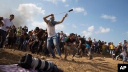 Palestinski demonstrant baca kamenice na izraelske vojnike tokom sukoba na granici u pojasu Gaze, 9. oktobar 2015.